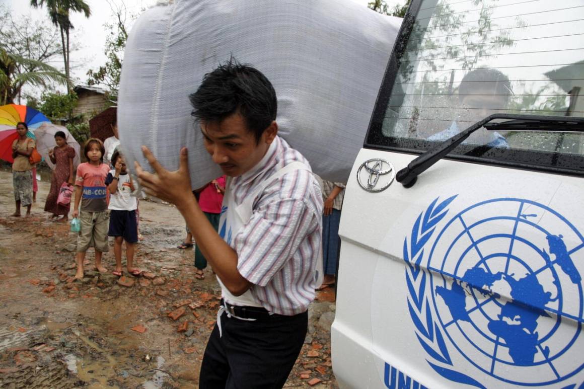 FNs logo symboliserer at nødhjelpen er uavhengig. Her deler FNs høykommisær for flyktninger ut tepper til overlevende fra en syklon i Yangon, Myanmar i 2008. Foto: UN Photo/UNHCR 